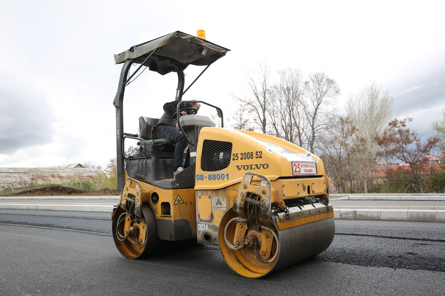 A vibratory roller compacting a fresh roller-compacted concrete surface on a job site.